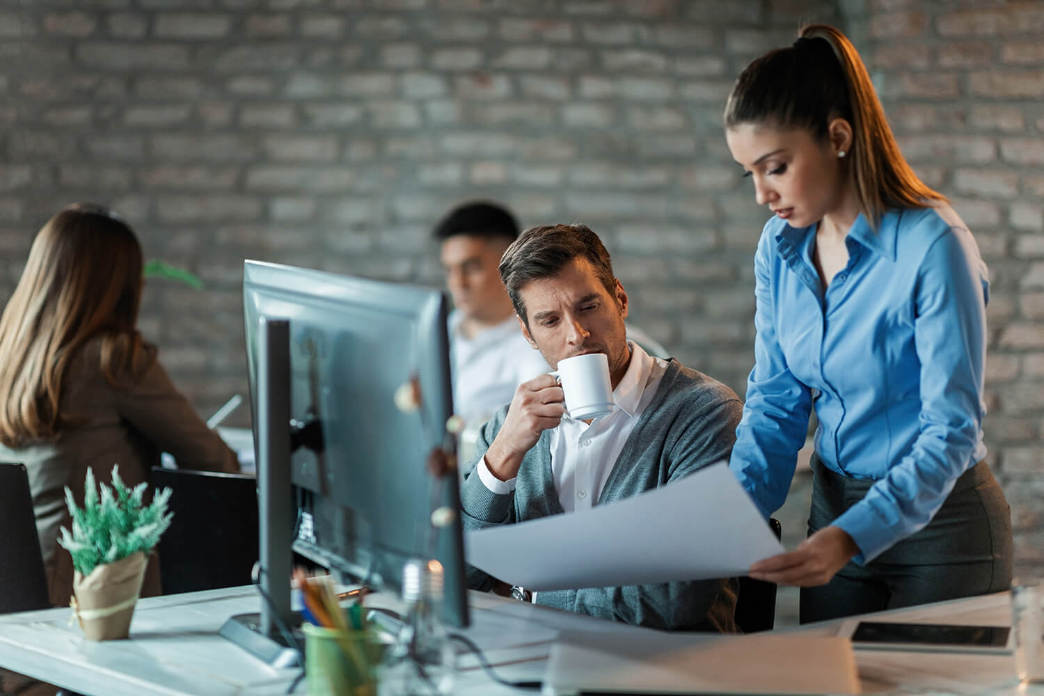 two-business-coworkers-analyzing-plans-while-working-project-office-focus-is-businessman-drinking-coffee